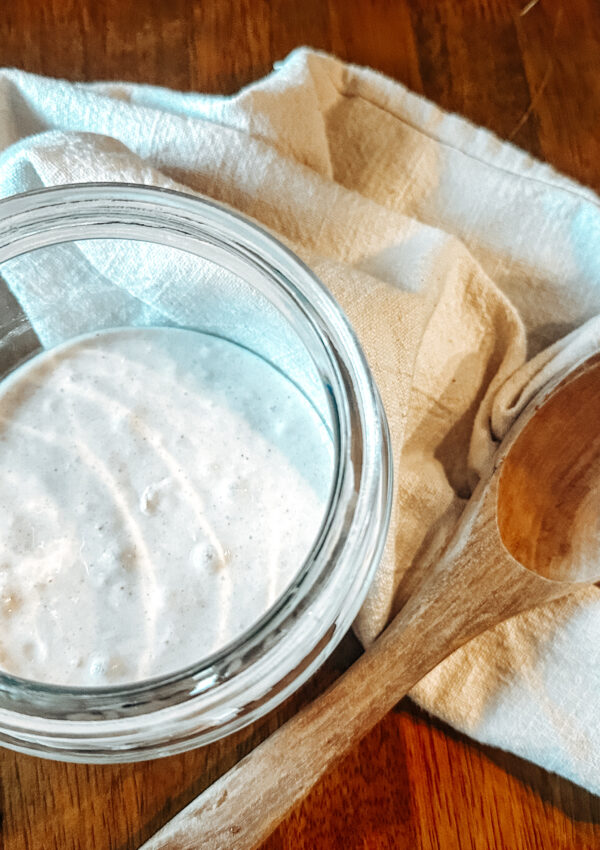 sourdough starter in glass jar with wood spoon
